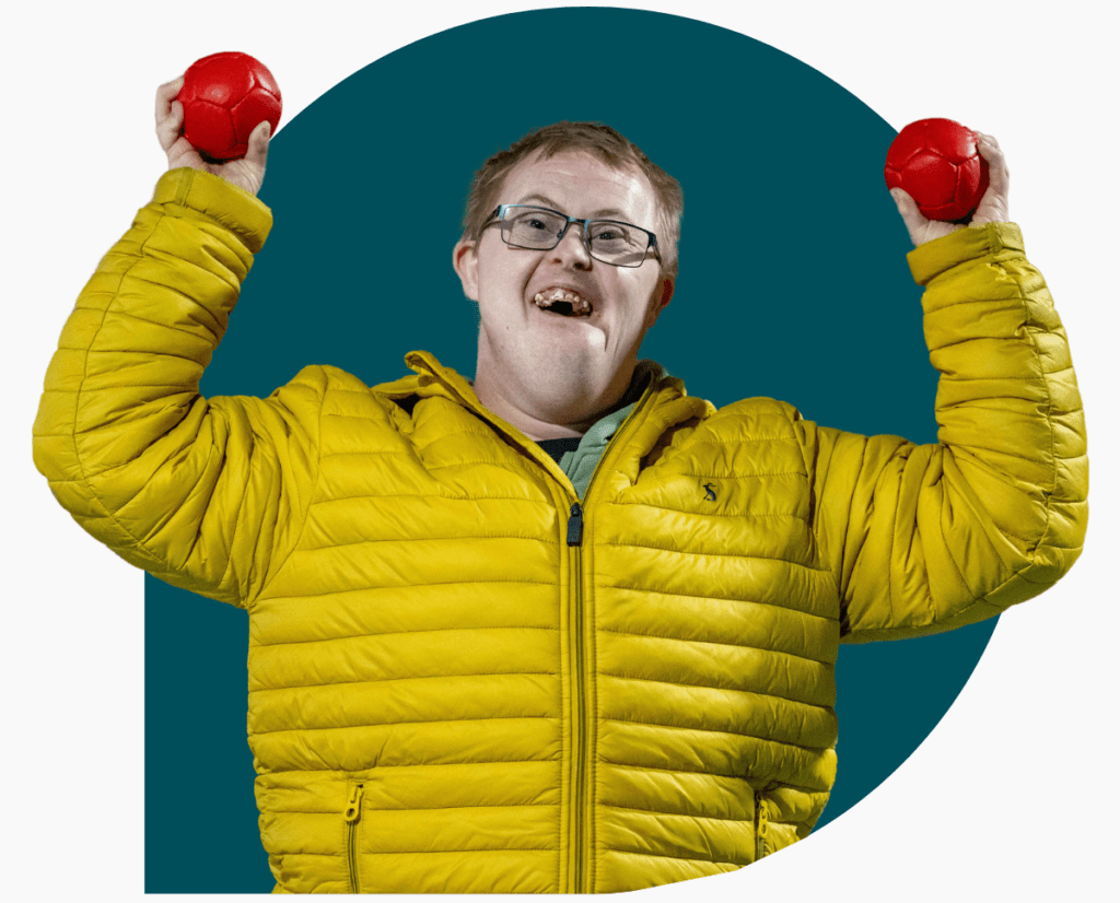 Man holding two balls victoriously over his head and smiling 