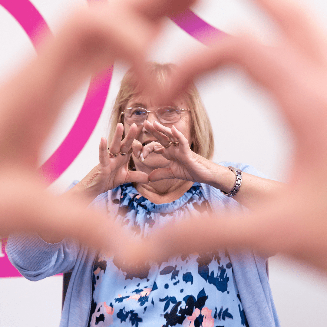 An older lady making a heart shape with her hands