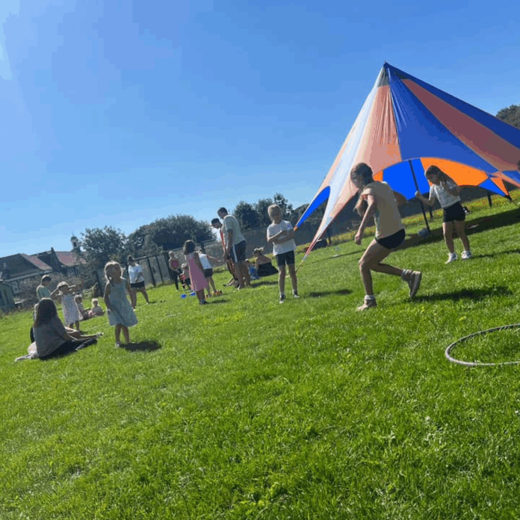 Children performing circus tricks in a field next to a circus tent