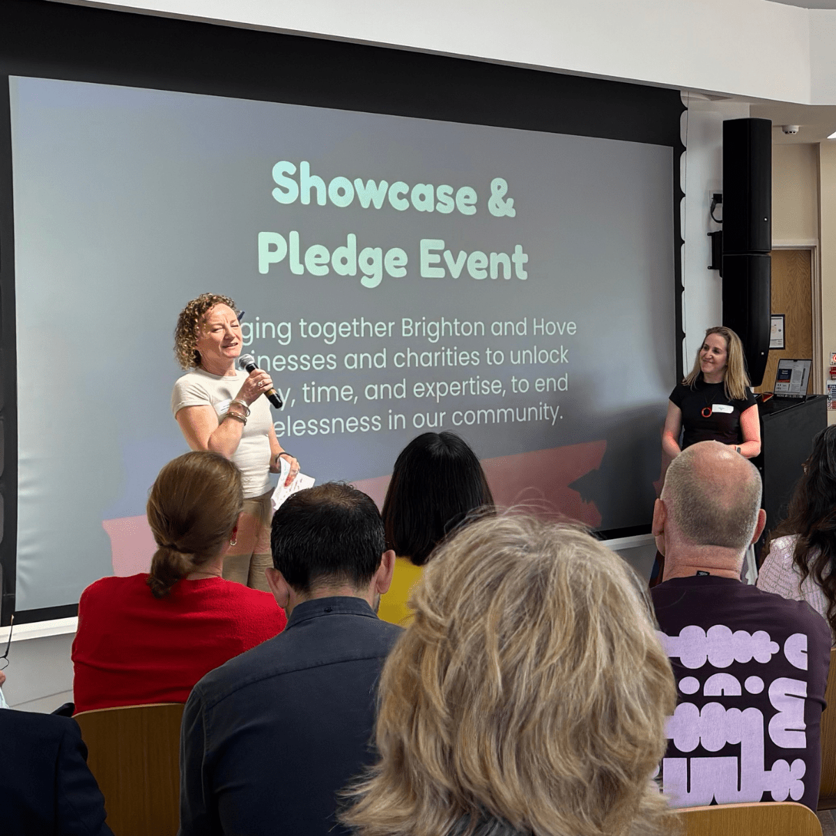 Kate welcoming the guests to the event in front of a slide saying Showcase & Pledge event