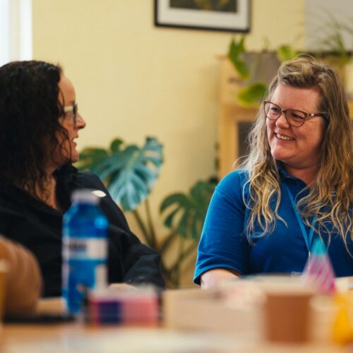 Hannah talking to a parent at a table during a session